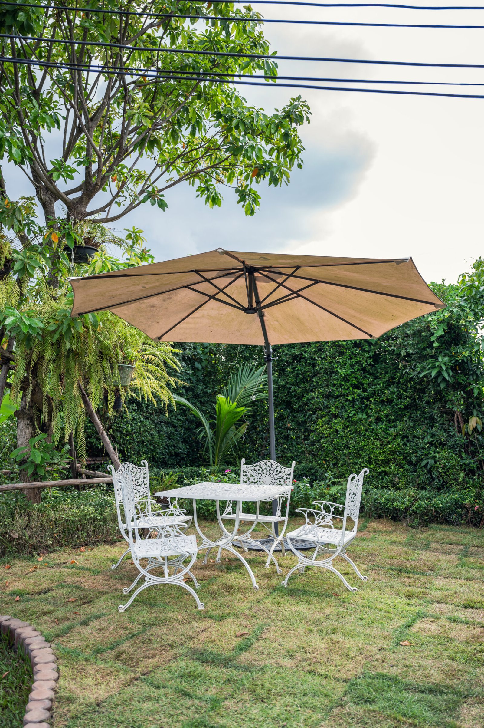 Set of white table with chairs and umbrella in the garden on backyard